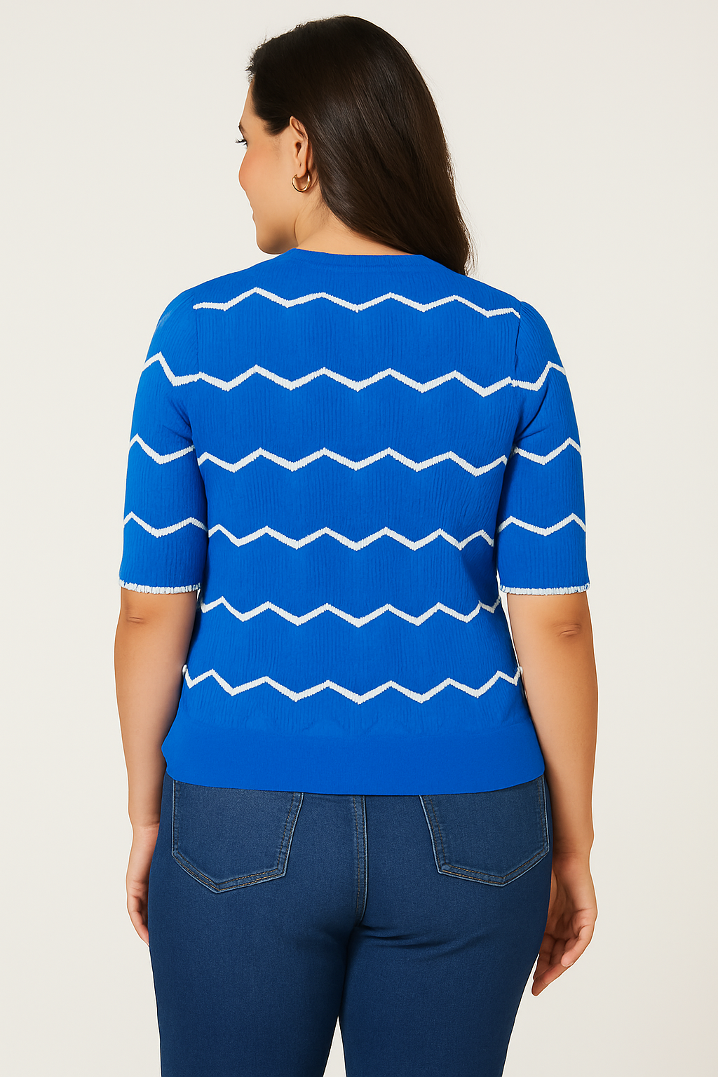 Back view of Jaclyn Smith Short-Sleeve Chevron Knit Sweater in vibrant blue with white chevron patterns, paired with medium-wash denim jeans, highlighting the sweater’s textured design.